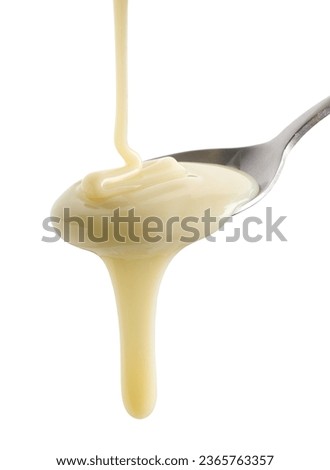 condensed milk pouring in spoon isolated on white background Royalty-Free Stock Photo #2365763357