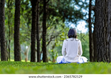 Woman relaxingly practicing meditation in the pine forest to attain happiness from inner peace wisdom with morning light for healthy mind and soul usage Royalty-Free Stock Photo #2365782129