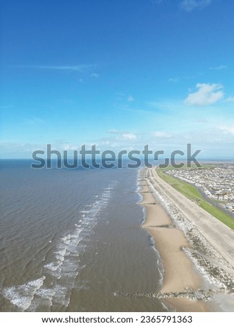 Aerial view of the coast of Fleetwood Lancashire with waves crashing and a blue sky background.
