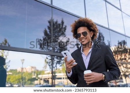 Cool businessman with sunglasses using phone standing in a financial district Royalty-Free Stock Photo #2365793113
