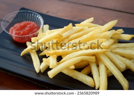 Salted French fries in black platr on a wooden table