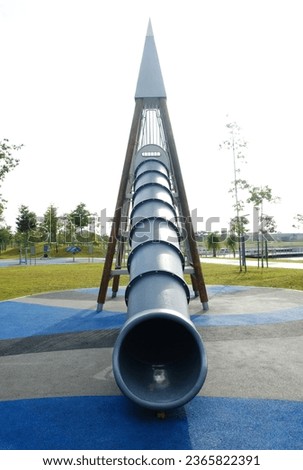A picture of tall slide at the park in the morning.