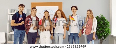 Group of cheerful international university students representing their countries holding flags. Six male and female students in classroom stand in row and smile at camera. Panoramic web banner. Royalty-Free Stock Photo #2365825949