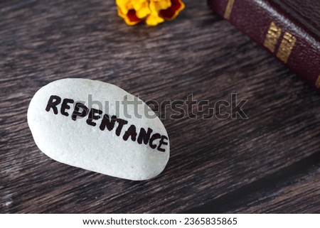 Repentance handwritten word on stone with closed holy bible book and flower on wooden background. Copy space, close-up. Confession, forgiveness, repenting of sin, Christian biblical concept. Royalty-Free Stock Photo #2365835865
