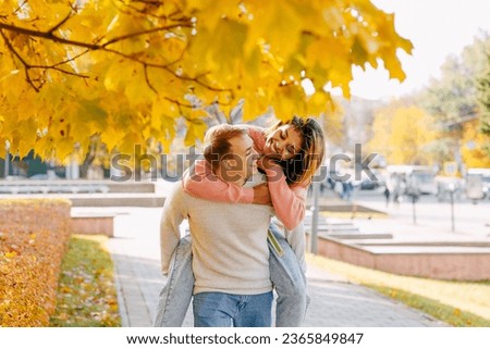 a young couple in love in a mixed marriage carelessly spend time in an autumn city park Royalty-Free Stock Photo #2365849847