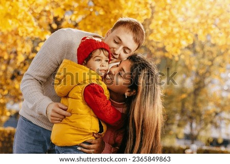an international family with their child in the autumn park on a walk. Warm feelings and emotions Royalty-Free Stock Photo #2365849863