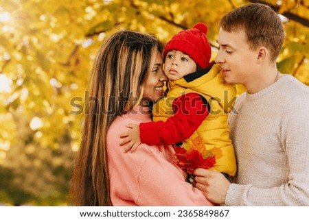 an international family with their child in the autumn park on a walk. Warm feelings and emotions Royalty-Free Stock Photo #2365849867