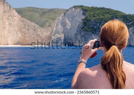 A woman takes a photograph f the shipwreck at Naviago Bay, Zante, Zakynthos