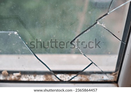 Broken glass in a plastic window in a house, on a green background. Broken glass, cracks in the glass. Selective focus.
