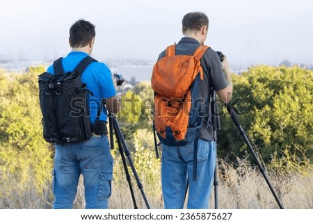 Two photographers take pictures standing on the hill