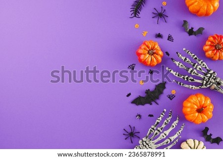 Infusing your home with the spooky charm of Halloween. Top view flat lay of scary skeleton arms, colorful pumpkins, spooky decor on violet background with ad space
