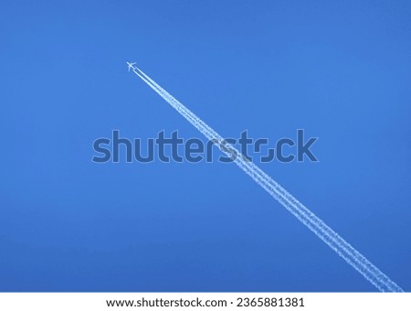 Big white two engine passenger supersonic aircraft flying from right to left high in clear blue cloudless sky leaving long white trace Royalty-Free Stock Photo #2365881381