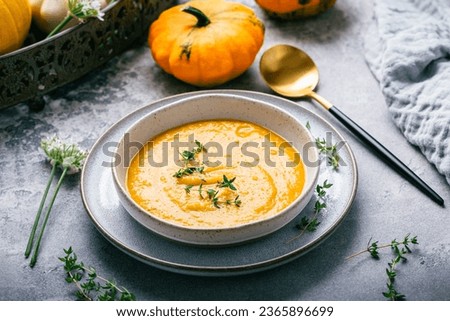 Pumpkin soup with pumpkin seeds served in bowl on rustic kitchen table
