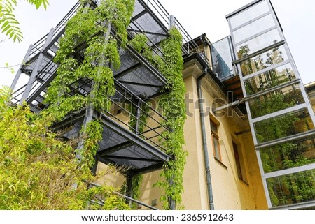 Sightseeing at City of Ljubljana with close-up of metal balconies of yellow building covered with plants on a cloudy summer day. Photo taken August 9th, 2023, Ljubljana, Slovenia.