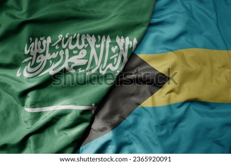 big waving realistic national colorful flag of saudi arabia and national flag of bahamas . macro