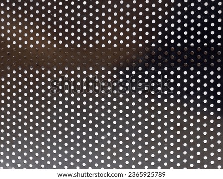 Horizontal black metal surface texture background with circle hole pattern.
