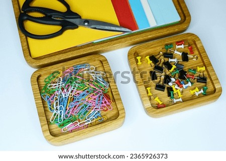 paper clips, scissors, colored paper, paper clip on the table in wooden organizers. stationery