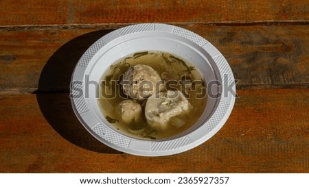 a picture of a meatball with soup served on a white plate called Bakso. Bakso are a very famous Indonesian specialty. The manufacturing technique is heavily influenced by Chinese culture