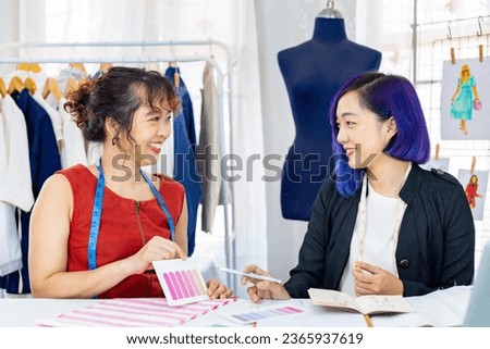 Team of fashionable freelance dressmakers choosing design and pantone for new custom made dress while working in the artistic workshop studio for fashion design and clothing business industry