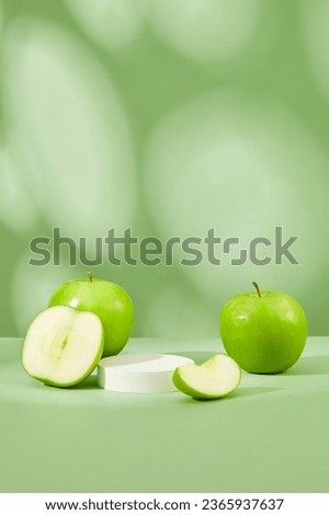 Round-shaped podium in white color is displayed on pastel background with green apple. Blank space on the podium for product presentation of Green Apple (Malus domestica) extract