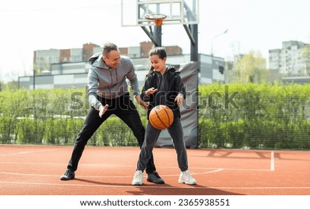 father and daughter playing basketball in the street