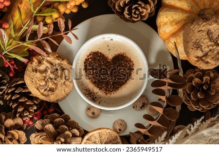Cozy autumn themed picture. Centered coffee cup with love heart, surrended by leaves, cookies, pumpkin and other decorations. 