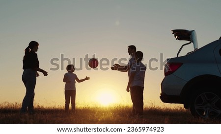 Family play, Travelling by car. Happy family travels by car. Parents, children stopped at campsite by car, Toy ball. Dad with child son, mother, children play with ball, next to car, beautiful sunset