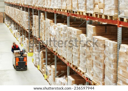 Electric forklift pallet stacker truck equipment at work in warehouse Royalty-Free Stock Photo #236597944