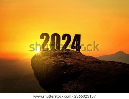 New Year 2024 at sunset. Silhouette 2024 stands on a mountain with sun rays at sunrise, creative idea. Year 2024, concept Royalty-Free Stock Photo #2366023157