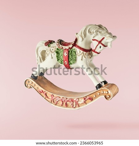 Christmas card. Falling in the air Christmas bauble in the shape of rocking horse isolated on pink background. Christmas figurine. Levitation or zero gravity conception. High resolution image. Royalty-Free Stock Photo #2366053965