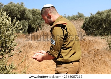 Religious Israeli soldier with a kippah on his head holds the Tanakh (Hebrew Bible) in his hands. The blurry inscription on the scripture is translated from Hebrew as Tanakh Royalty-Free Stock Photo #2366057319