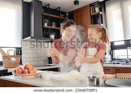 Beautiful happy mother and daughter preparing an apple pie at home kitchen. Autumn fun family activities. Baking together. Royalty-Free Stock Photo #2366070891
