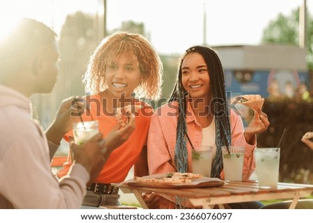 Smiling happy African American friends eating pizza drinking cocktail outdoors cafe near university campus. Concept of communication, meeting, celebration