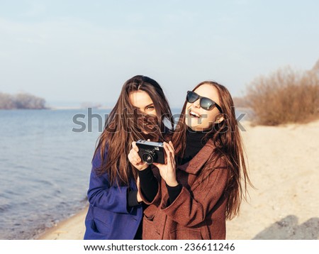 Beautiful young girls taking pictures on the beach in front of the sea. Outdoor lifestyle portrait