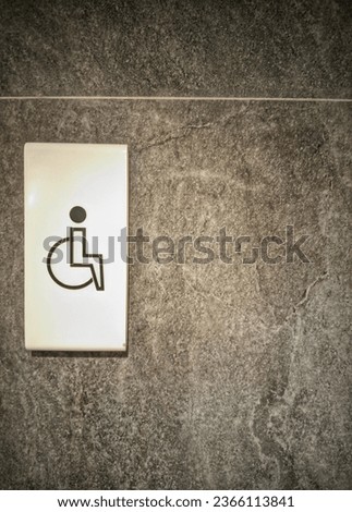 A toilet with a handicap sign on the wall, accessible for the disabled.