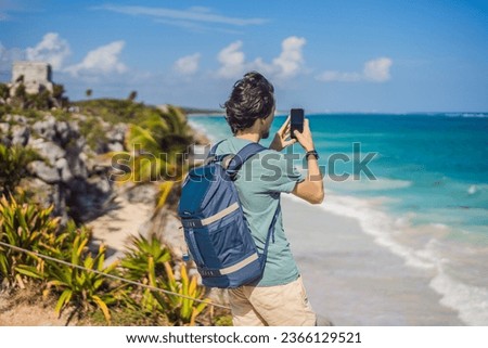 Male tourist enjoying the view Pre-Columbian Mayan walled city of Tulum, Quintana Roo, Mexico, North America, Tulum, Mexico. El Castillo - castle the Mayan city of Tulum main temple Royalty-Free Stock Photo #2366129521