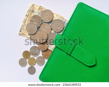 In the picture, there are currencies of many countries, silver and gold bills and coins stacked together, a green wallet and a calculator.

