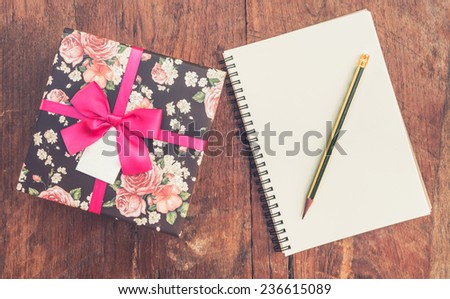 vintage gift box on wood background with notebook and pencil.