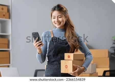 Female entrepreneur using mobile phone and preparing orders for shipping in a warehouse. Royalty-Free Stock Photo #2366154839