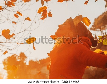 Overjoy and happiness emotion people. One woman throwing leaves in the air at the park during warm color red sunset in autumn season. People and freedom or joy feeling. Love nature. Playing outdoor Royalty-Free Stock Photo #2366162465