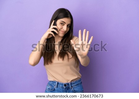 Young caucasian woman using mobile phone isolated on purple background counting five with fingers