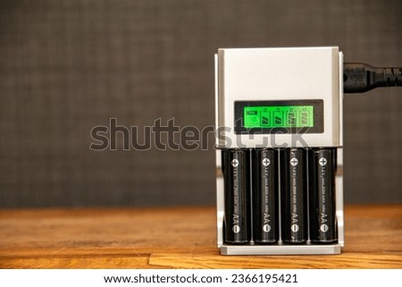 Rechargeable batteries in a battery charger. Four AA batteries in a charger with a green display showing the level of charge. NI-MH and LI-MH battery. Copy space. Selective focus on the batteries.  Royalty-Free Stock Photo #2366195421