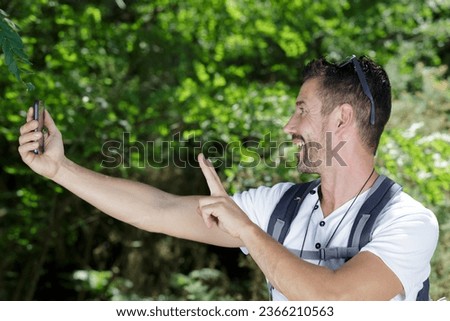 man with backback making victory sign for selfie