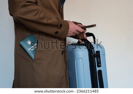 Translation: "military id". Man in coat with smartphone in hand, holding travel suitcase and army document for rookie, veteran, soldier in pocket on white background 