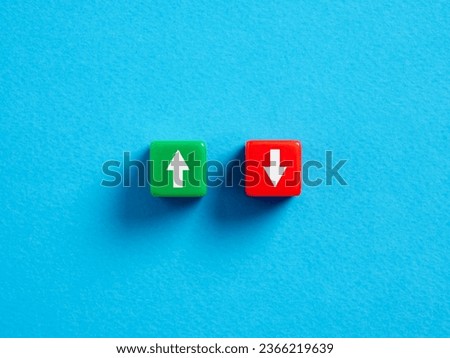 Growth or loss. Risk taking. Going up or down. Economic growth or business investments. Up and down arrows on colorful cubes on blue background.