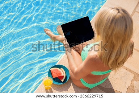Woman using tablet computer on vacation by the pool, view from above