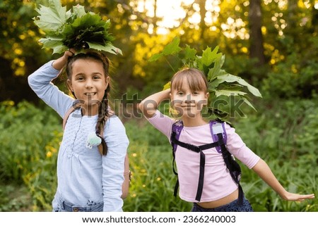 Schoolgirls picking autumn leaves for drying. School project making herbarium from dried leaves. Girl prepared leaves for autumn craft. girls walking in autumn park. Royalty-Free Stock Photo #2366240003