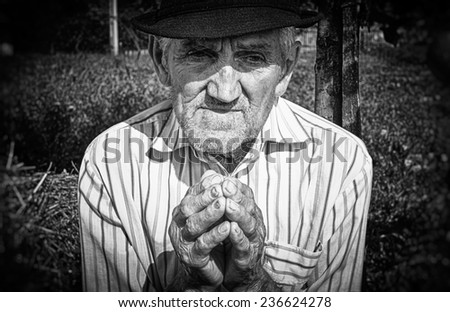 Old man's hands, praying in the yard. Black and white picture.