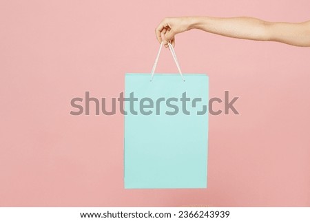 Close up cropped female holding in hand paper package bag after shopping isolated on pastel plain light pink color background studio. Black Friday sale buy day concept. Copy space advertising mock up