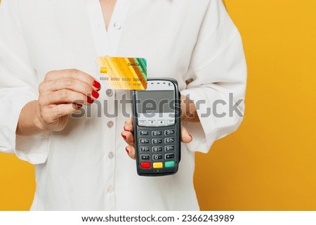 Cropped young happy woman she wears white shirt casual clothes hold wireless modern bank payment terminal to process acquire credit card isolated on plain yellow background studio. Lifestyle concept